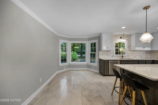 a large kitchen with granite countertop a stove a sink a window and dining table
