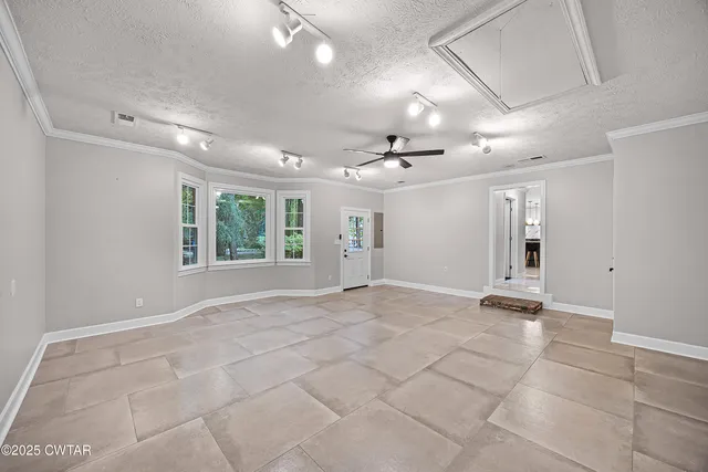 a view of an empty room with window and chandelier fan