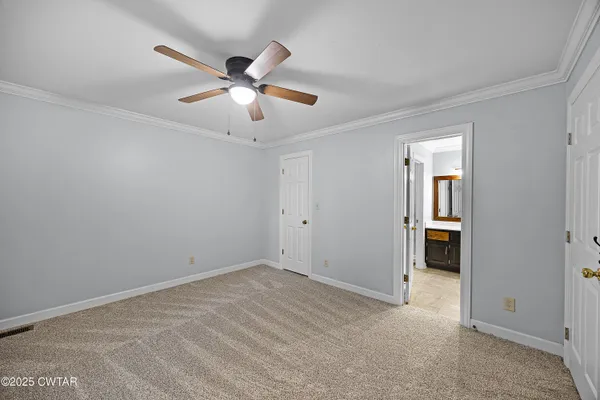 a view of an empty room with chandelier fan