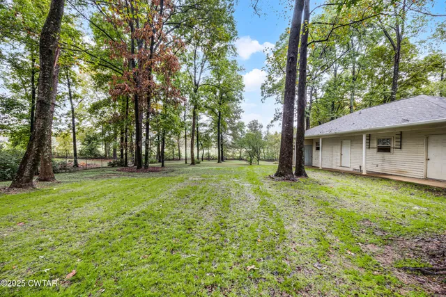 a view of a house with backyard and trees