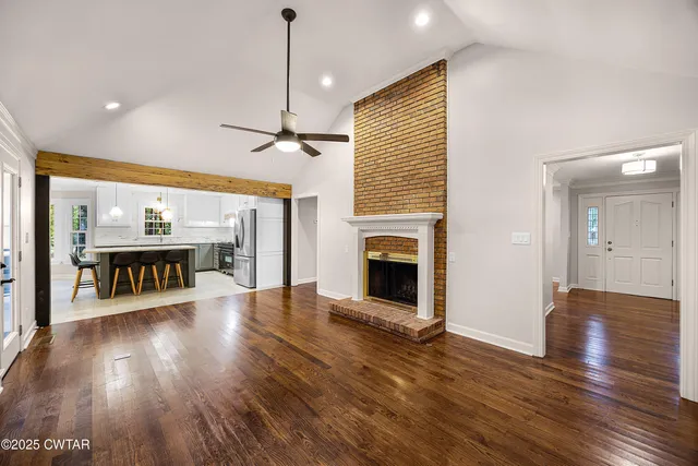 a view of a big room with wooden floor fire place and windows