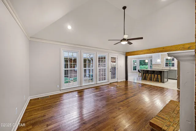 a view of an empty room with wooden floor and a window
