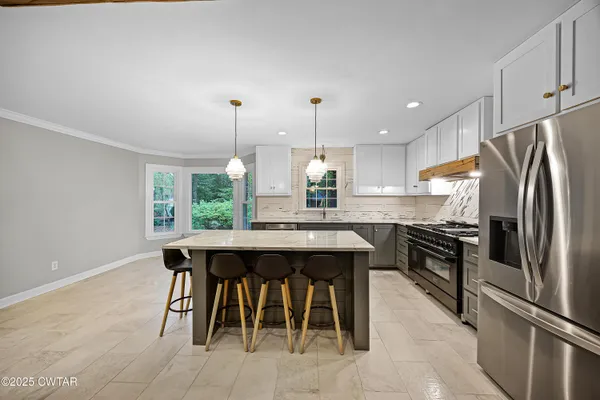 a kitchen with stainless steel appliances granite countertop a sink a stove a refrigerator and island with wooden floor