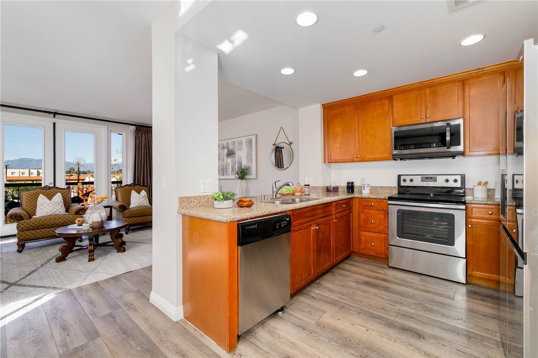 408 West Main Street, Unit 2G Alhambra, CA 91801 - Photo 8 of 30 a large kitchen with stainless steel appliances granite countertop a stove top oven a sink a dining table and chairs with wooden floor