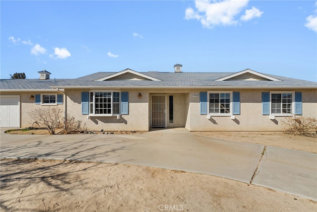 57622 Sierra Way Yucca Valley, CA 92284 - Photo 6 of 75 a front view of a house with a garden and patio