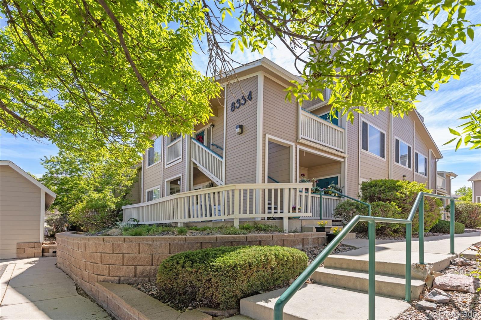 8334 Pebble Creek Way, Unit 201 Highlands Ranch, CO 80126 - Photo 27 of 28 a view of a brick house with a small yard plants and large tree