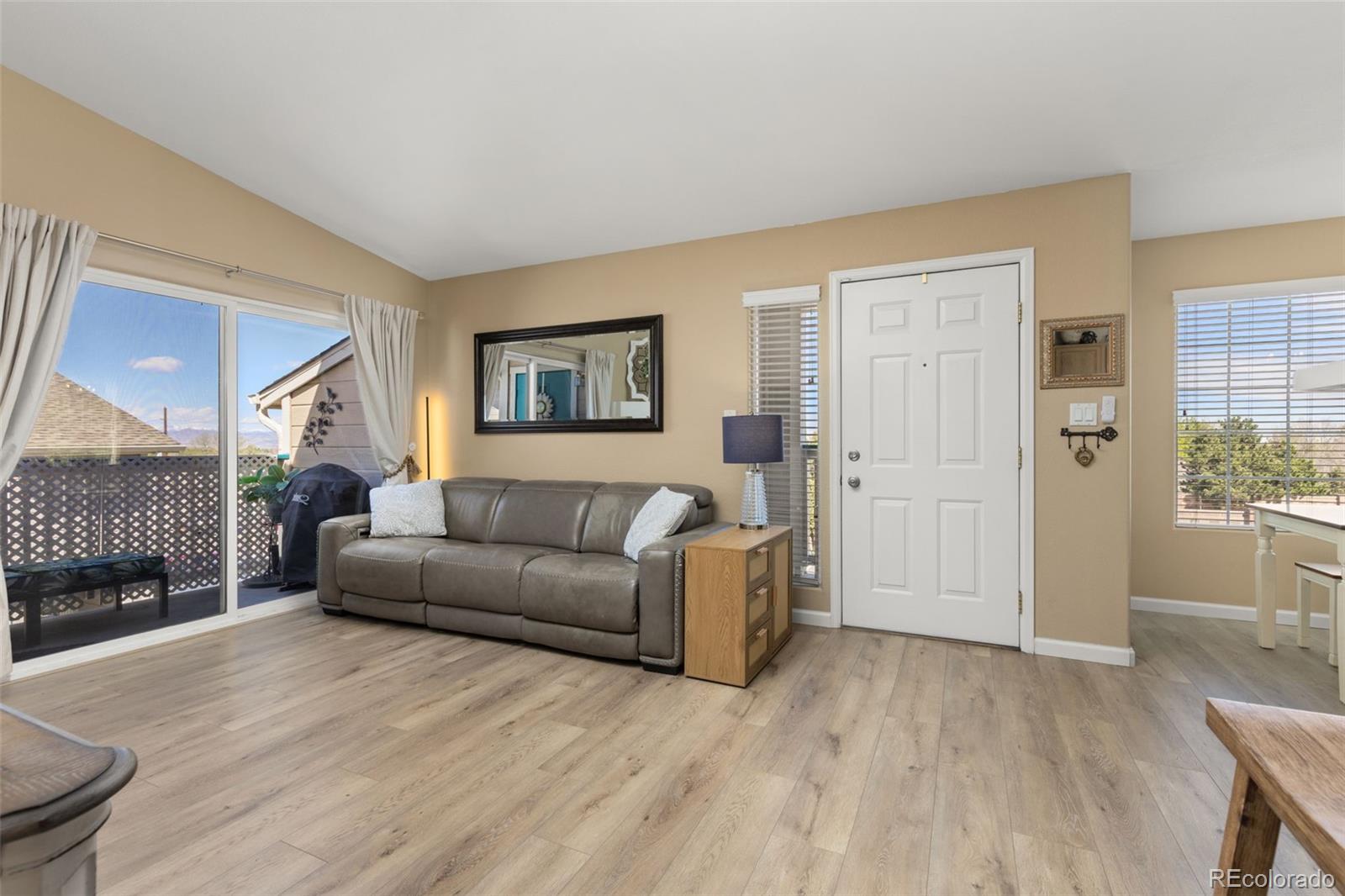 8334 Pebble Creek Way, Unit 201 Highlands Ranch, CO 80126 - Photo 4 of 28 a living room with furniture a large window and wooden floor