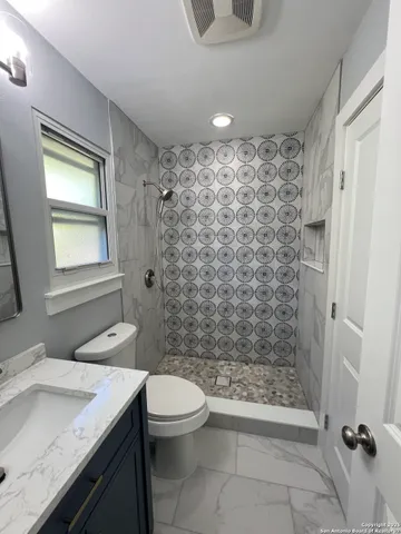 a bathroom with a sink a toilet and shower