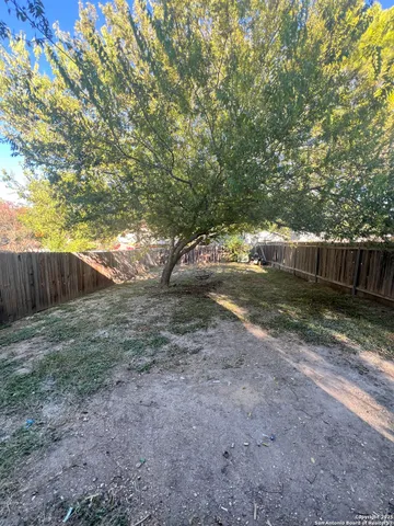 a view of a yard with wooden fence