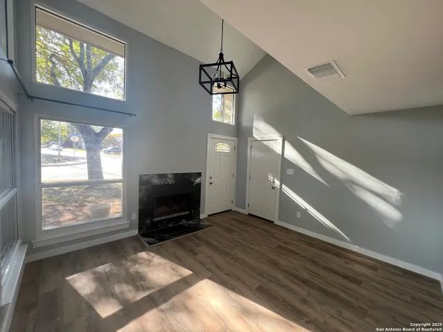 a view of an empty room with wooden floor fireplace and a window