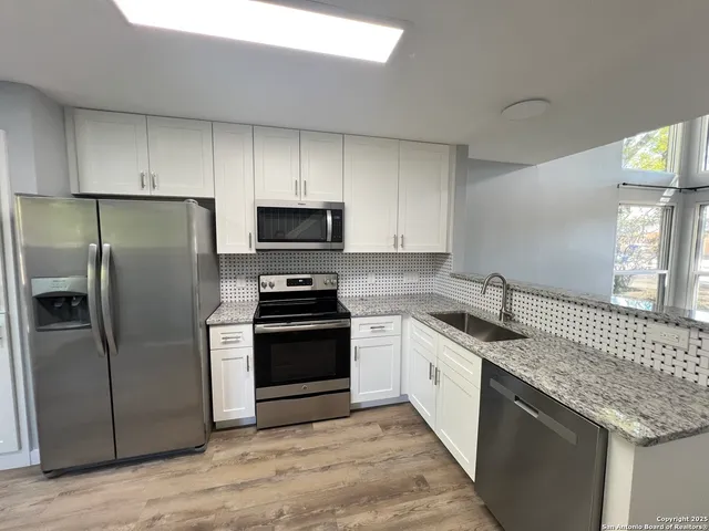 a kitchen with stainless steel appliances granite countertop a sink a stove a refrigerator a microwave and cabinets