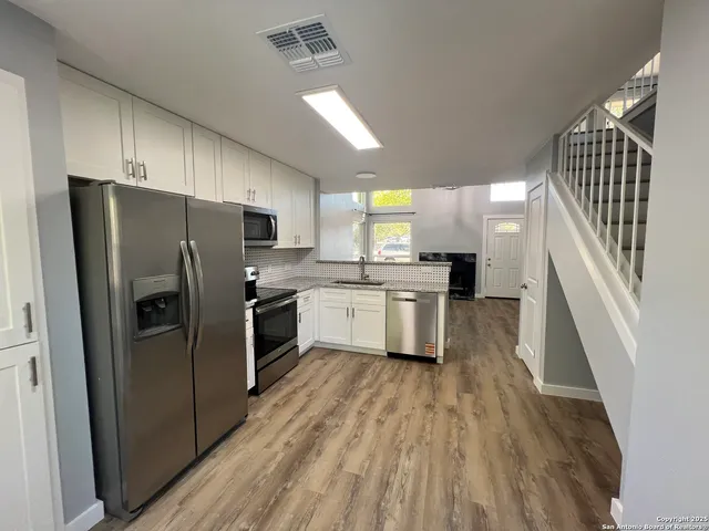 a kitchen with a refrigerator a sink and cabinets