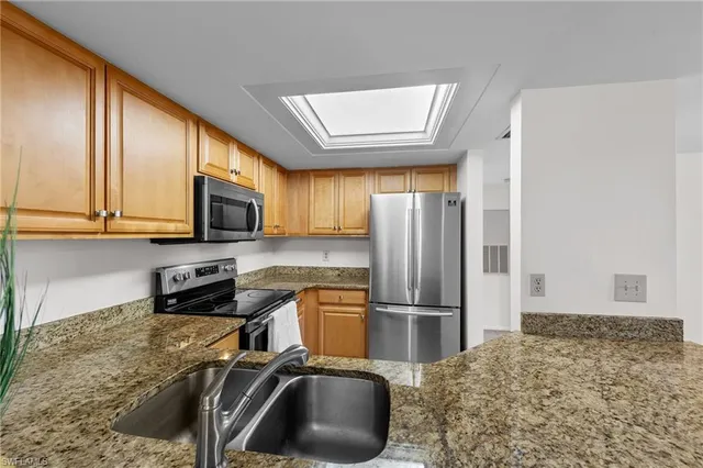 a kitchen with stainless steel appliances granite countertop a sink a stove and a microwave