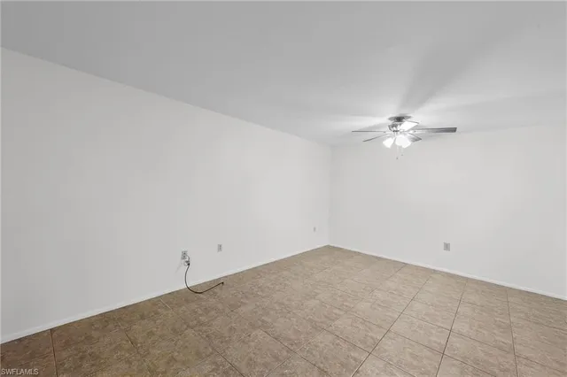 an empty room with a ceiling fan and window