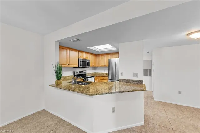 a kitchen with stainless steel appliances granite countertop a refrigerator a stove and a sink with wooden floor