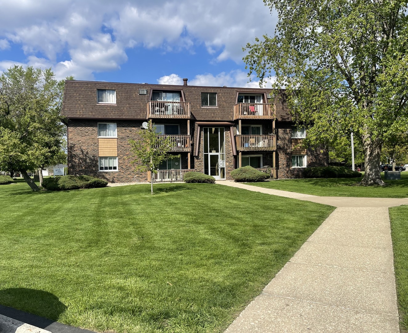 a view of a big building with a big yard and large trees