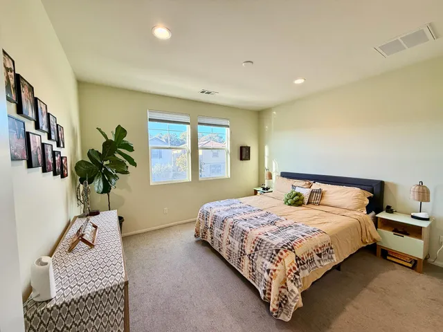 a bedroom with a bed a dresser and next to a window