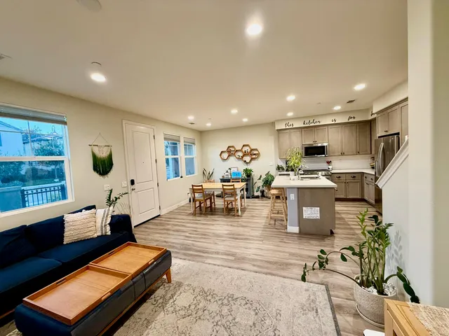 a living room with furniture kitchen view and a large window