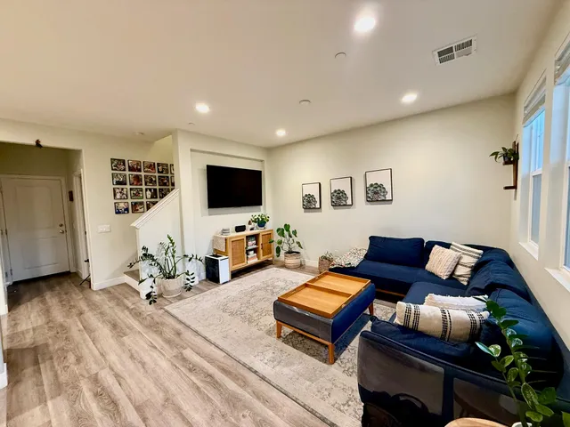 a living room with furniture a flat screen tv and kitchen view
