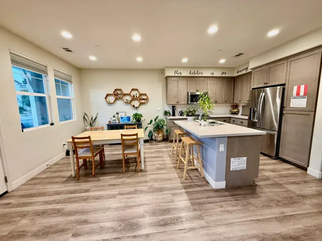 a kitchen with stainless steel appliances granite countertop a table chairs sink refrigerator and microwave