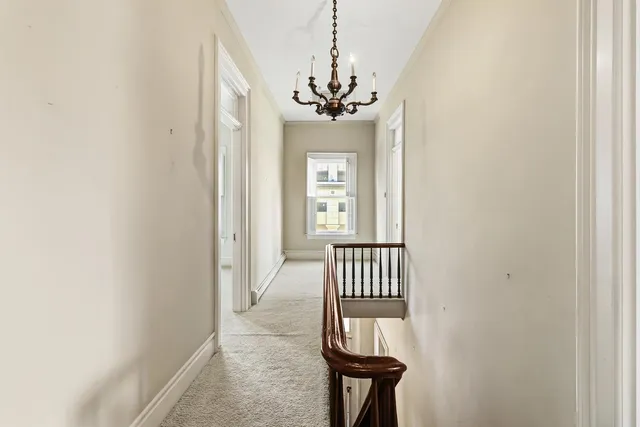 an empty room with a chandelier fan and windows