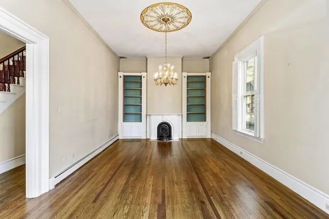 a view of an empty room with a window and wooden floor