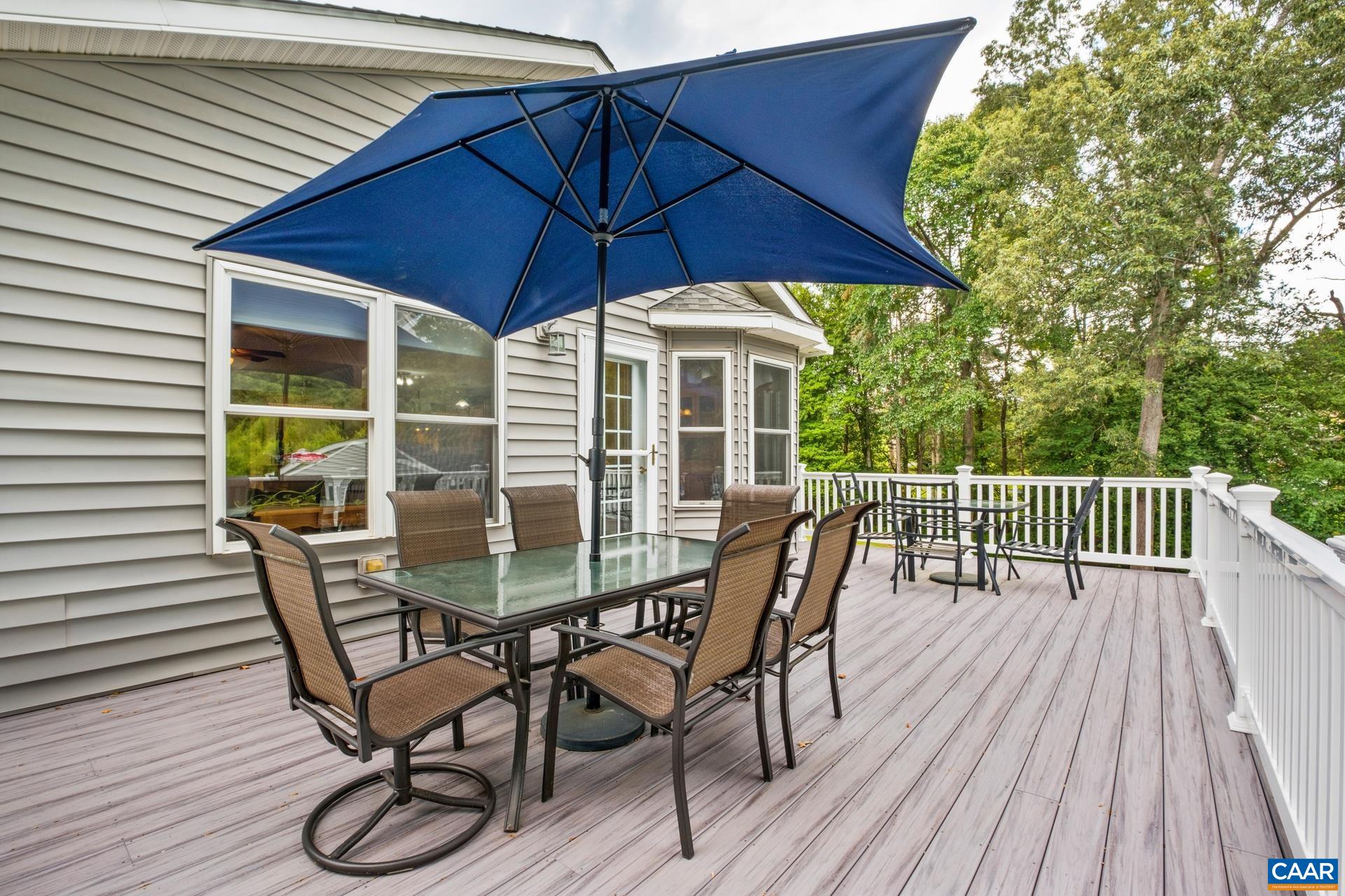 162 Rolling Hills Road Ruckersville, VA 22968 - Photo 36 of 48 a view of a wooden deck with table and chairs under an umbrella