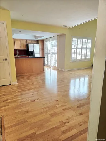 a view of kitchen and empty room with wooden floor