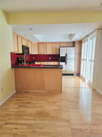 a view of a kitchen with kitchen island a sink wooden floor and living room view