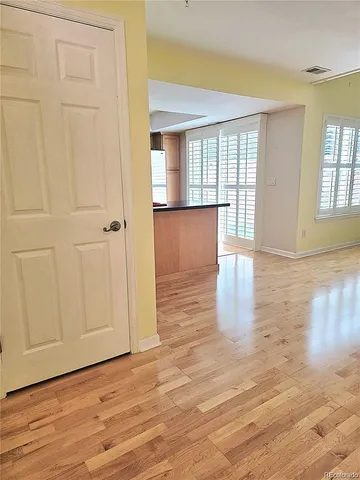 a view of an empty room with wooden floor and a window