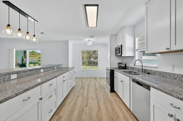a large kitchen with stainless steel appliances granite countertop a lot of counter space and wooden floors