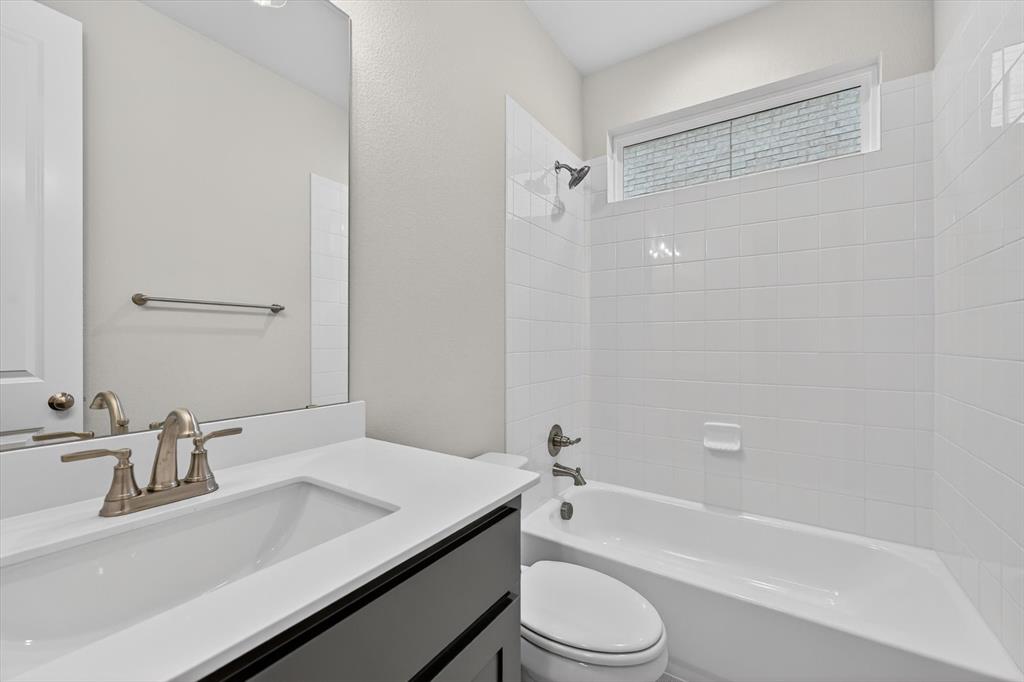 4123 Windy Point Court Oak Point, TX 75068 - Photo 20 of 29 Modern bathroom featuring a white single-basin vanity with a quartz countertop, dark wood-finish cabinetry, a full-size mirror, and brushed nickel fixtures