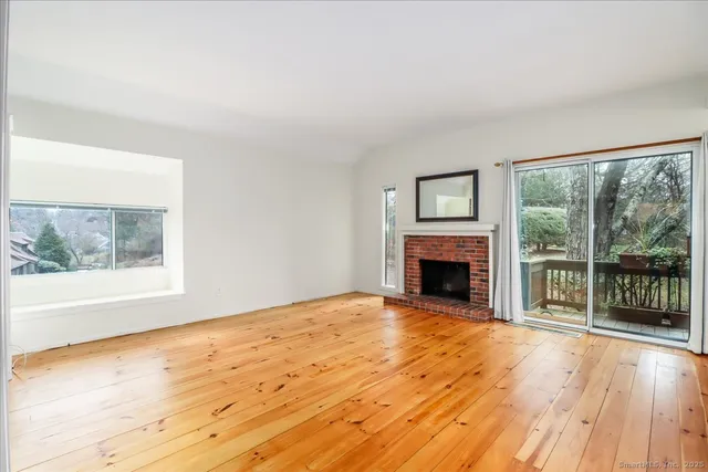 a view of empty room with wooden floor and fireplace