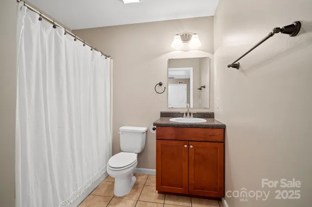 a bathroom with a granite countertop toilet a sink and a mirror
