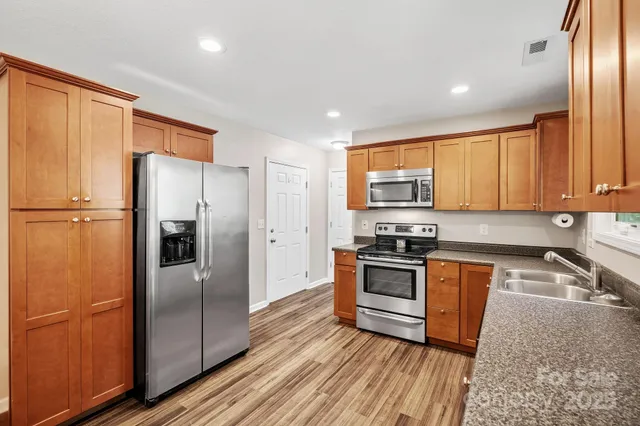 a kitchen with stainless steel appliances granite countertop a refrigerator stove and sink
