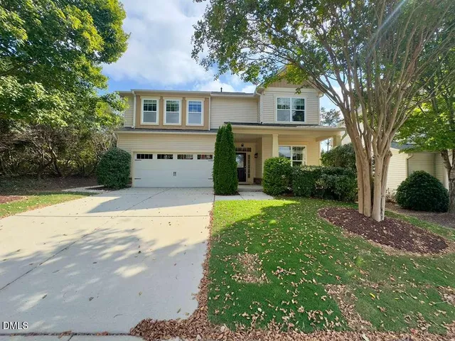 a front view of a house with garden and trees
