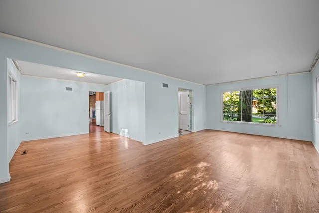 a view of an empty room with a window and wooden floor