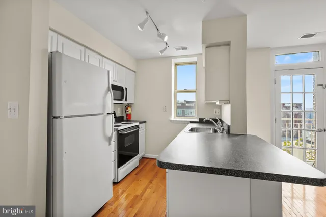 a kitchen with kitchen island a counter top space a sink a refrigerator and a window