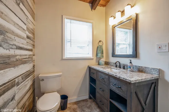 a bathroom with a granite countertop toilet sink and mirror