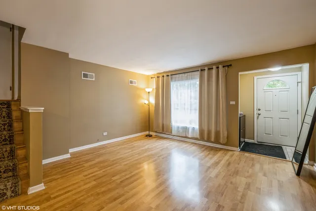 a view of an empty room with wooden floor and a bathroom