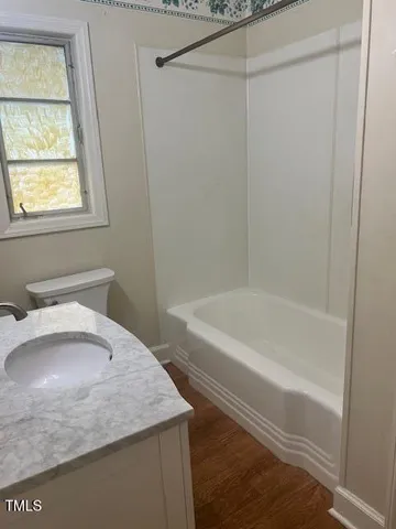 a bathroom with a granite countertop sink a toilet and bathtub