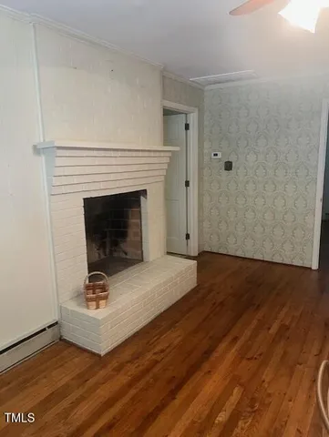 a view of an empty room with wooden floor and a fireplace