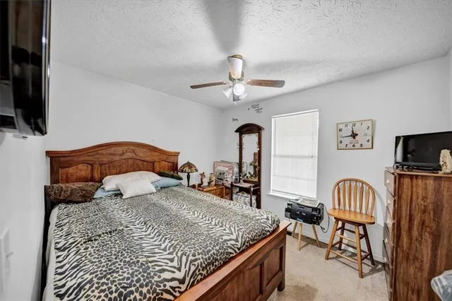 a bedroom with a bed a flat screen tv and a chandelier