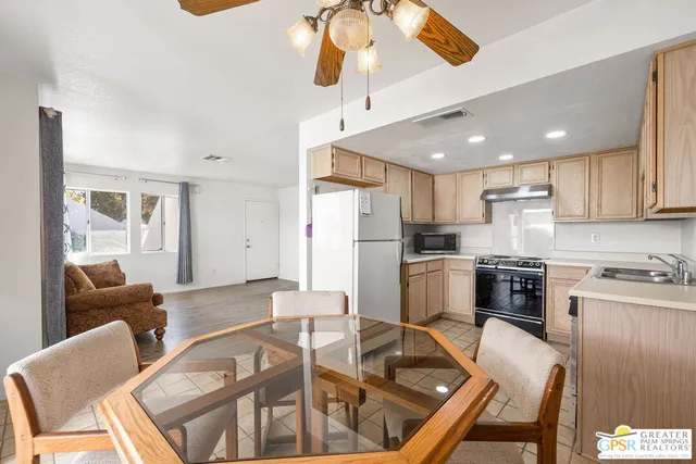 a kitchen with stainless steel appliances granite countertop a stove a refrigerator a kitchen island a table and chairs with wooden floor