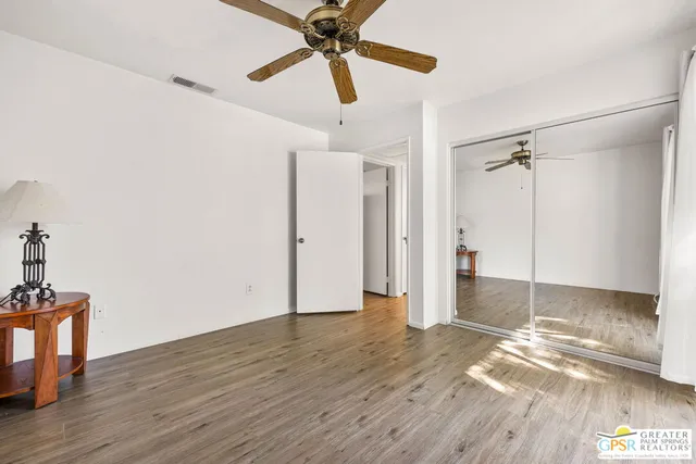 a view of a room with wooden floor and ceiling fan