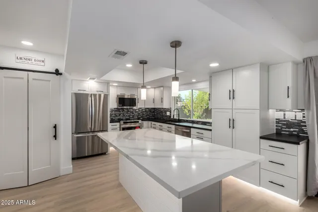 a large kitchen with stainless steel appliances kitchen island granite countertop a refrigerator and a stove top oven