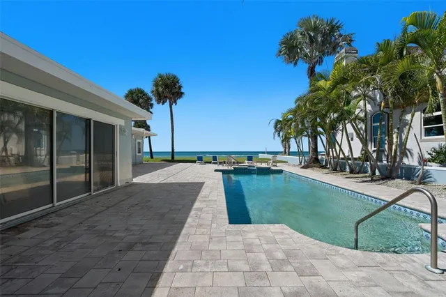 a view of a white house with a yard plants and palm trees