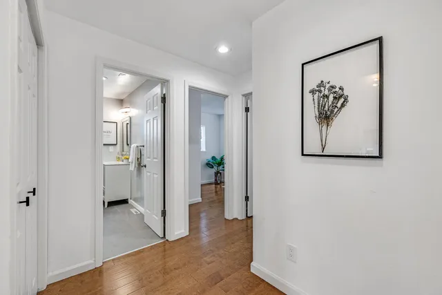 a view of a hallway with wooden floor and a bathroom