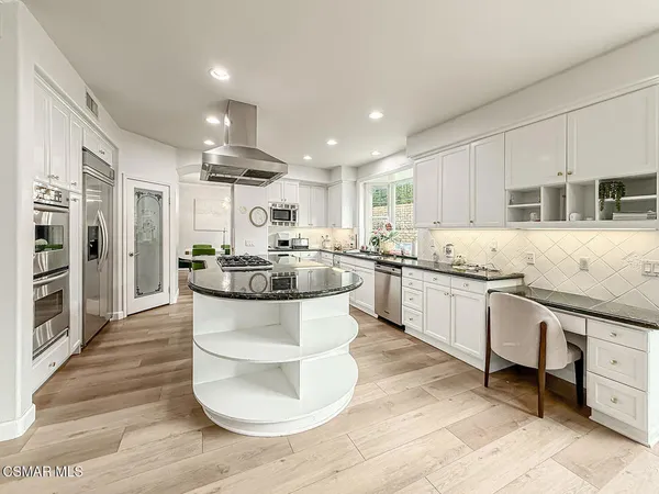 a large kitchen with stainless steel appliances kitchen island granite countertop a stove a sink a refrigerator and white cabinets