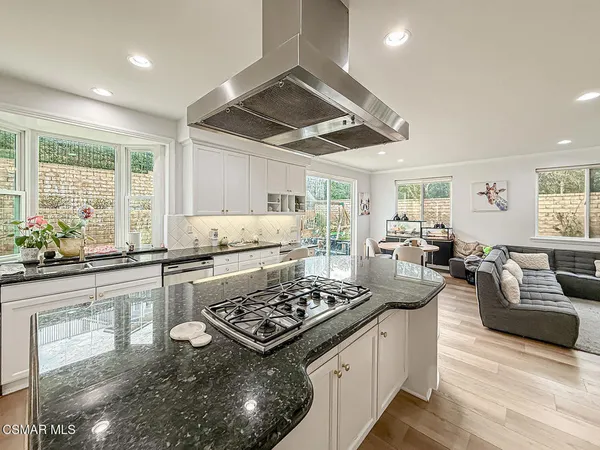 a kitchen with stainless steel appliances granite countertop a stove and a view of living room